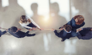 Rival business man and woman compete in office for the command by pulling the rope. double exposure